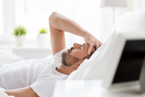 Man in bed with headache struggling with long Covid
